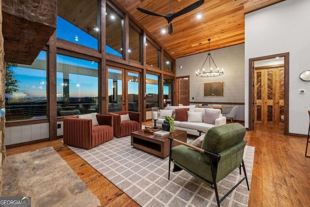 living room with wooden ceiling, high vaulted ceiling, ceiling fan with notable chandelier, and wood-type flooring