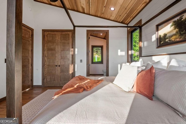 bedroom featuring ensuite bath, wooden ceiling, vaulted ceiling, two closets, and hardwood / wood-style flooring