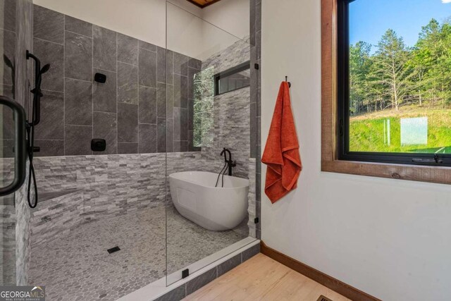 bathroom featuring wood-type flooring and separate shower and tub