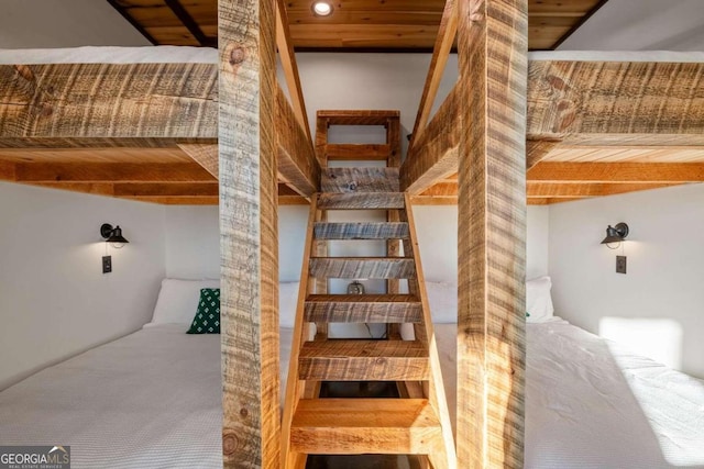 stairway with beamed ceiling, wood ceiling, and carpet floors