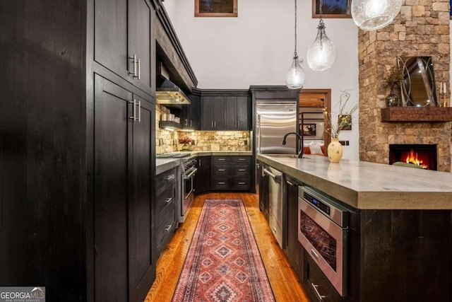 kitchen with a fireplace, tasteful backsplash, premium appliances, and hardwood / wood-style flooring