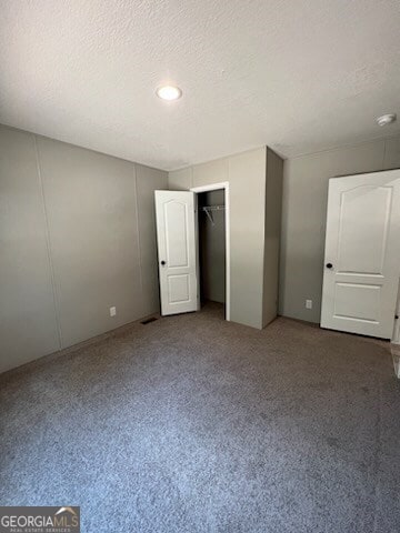 unfurnished bedroom with a closet and dark colored carpet