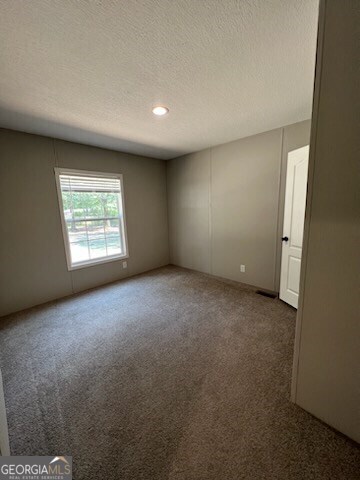 carpeted spare room featuring a textured ceiling