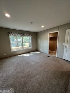 unfurnished bedroom featuring a closet, a walk in closet, and carpet flooring