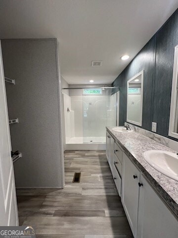 bathroom with hardwood / wood-style flooring, a shower, and double sink vanity