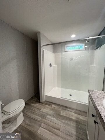 bathroom featuring wood-type flooring, a shower, vanity, and toilet