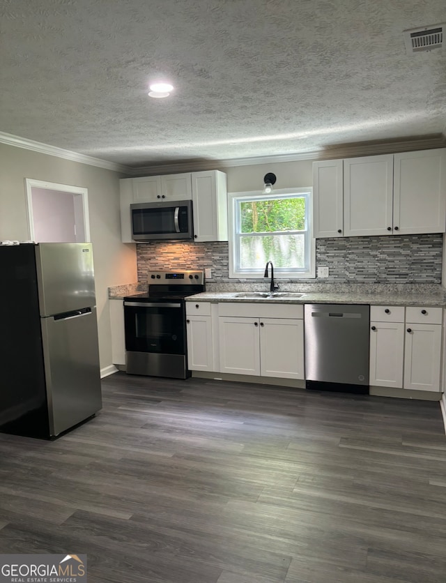 kitchen with ornamental molding, sink, appliances with stainless steel finishes, and white cabinetry