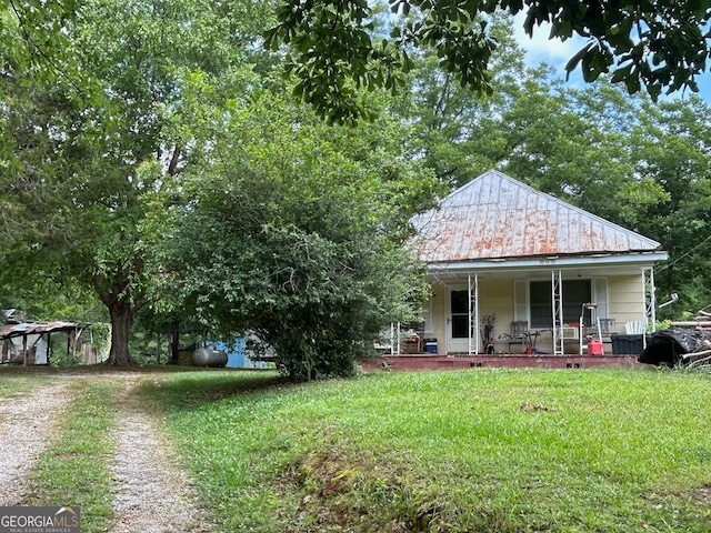 rear view of property featuring covered porch and a lawn