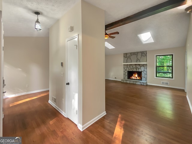 unfurnished living room featuring ceiling fan, a fireplace, dark wood-type flooring, and vaulted ceiling with beams