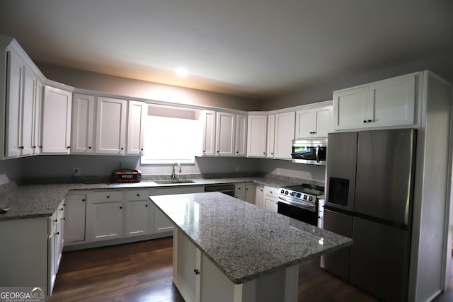 kitchen featuring dark hardwood / wood-style flooring, a kitchen island, stainless steel appliances, light stone countertops, and sink