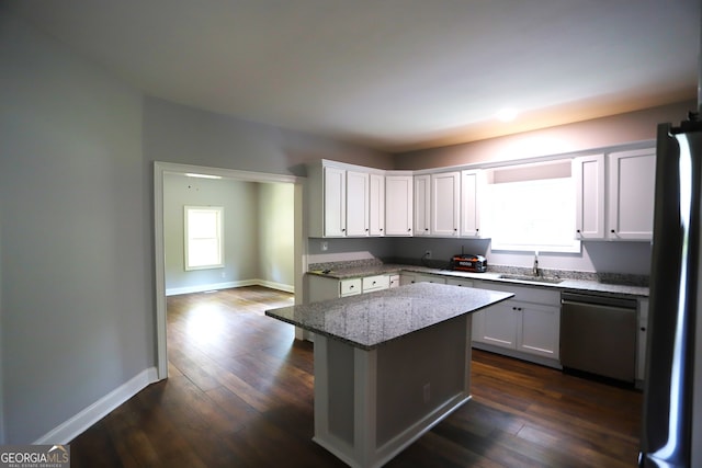 kitchen featuring appliances with stainless steel finishes, dark wood-type flooring, a wealth of natural light, and light stone counters