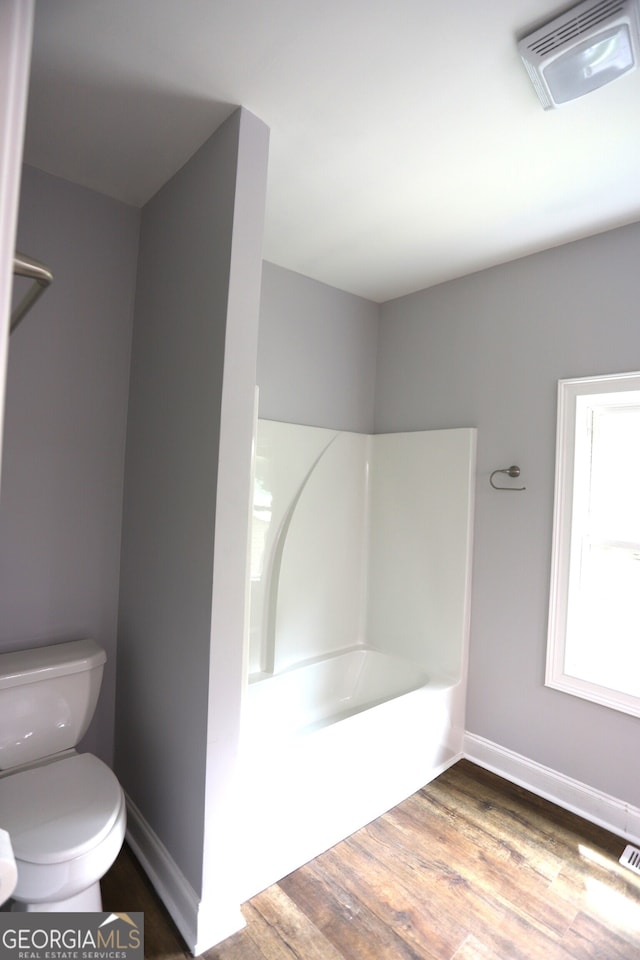 bathroom featuring toilet, hardwood / wood-style flooring, and bathtub / shower combination