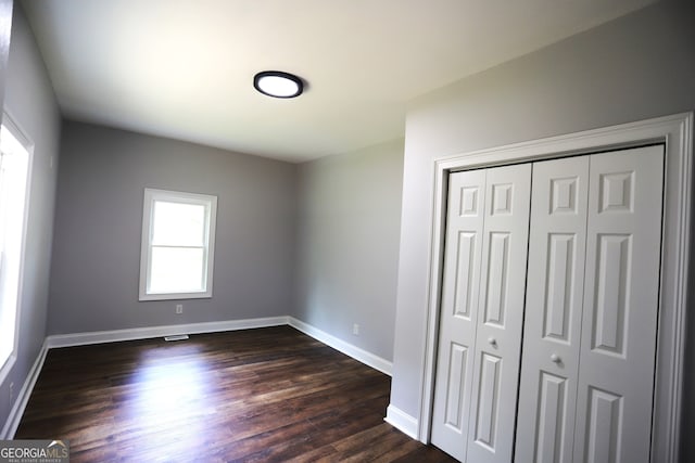 unfurnished bedroom with dark hardwood / wood-style floors and a closet