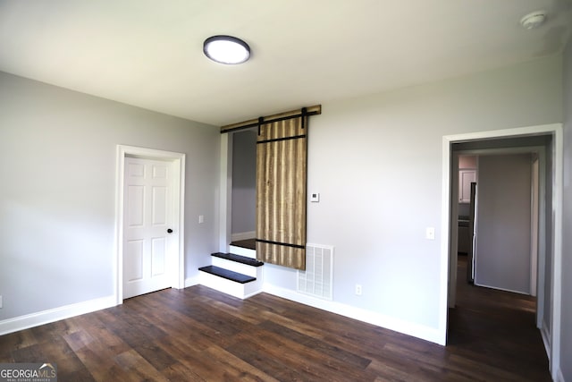 spare room with dark hardwood / wood-style flooring and a barn door