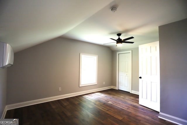 additional living space featuring a wall unit AC, dark hardwood / wood-style flooring, ceiling fan, and vaulted ceiling