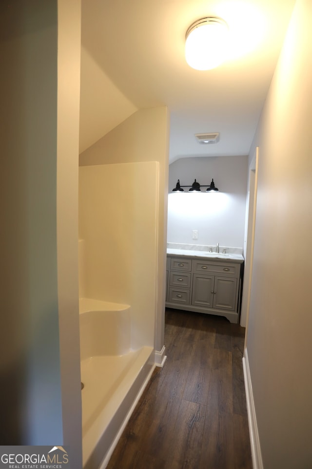 bathroom featuring vanity, hardwood / wood-style flooring, and vaulted ceiling