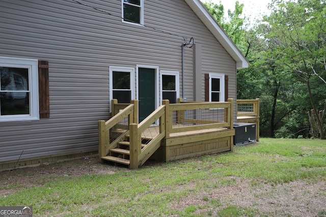 rear view of property with a deck, central air condition unit, and a lawn