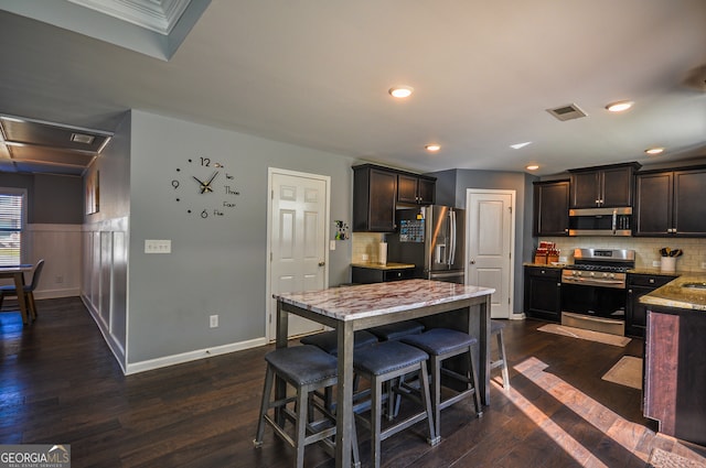 kitchen featuring dark brown cabinets, appliances with stainless steel finishes, backsplash, and dark wood-type flooring