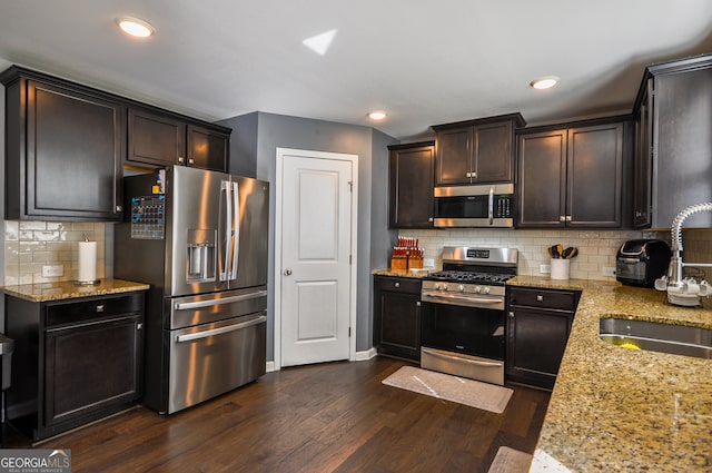 kitchen featuring light stone countertops, dark hardwood / wood-style floors, backsplash, stainless steel appliances, and sink