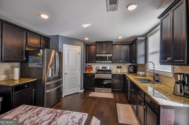 kitchen with appliances with stainless steel finishes, tasteful backsplash, dark wood-type flooring, and sink