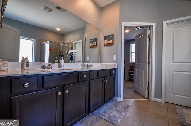 bathroom featuring a shower with door, dual sinks, oversized vanity, and tile floors