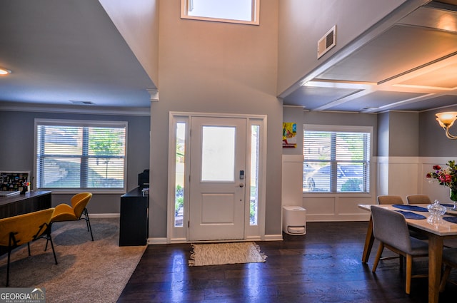 foyer entrance with plenty of natural light, crown molding, coffered ceiling, and dark wood-type flooring