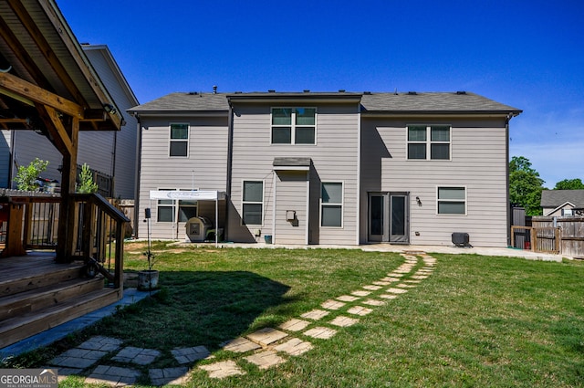 back of property featuring a deck and a lawn