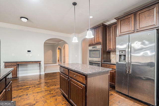 kitchen featuring dark stone counters, decorative light fixtures, a kitchen island, dark brown cabinetry, and stainless steel appliances