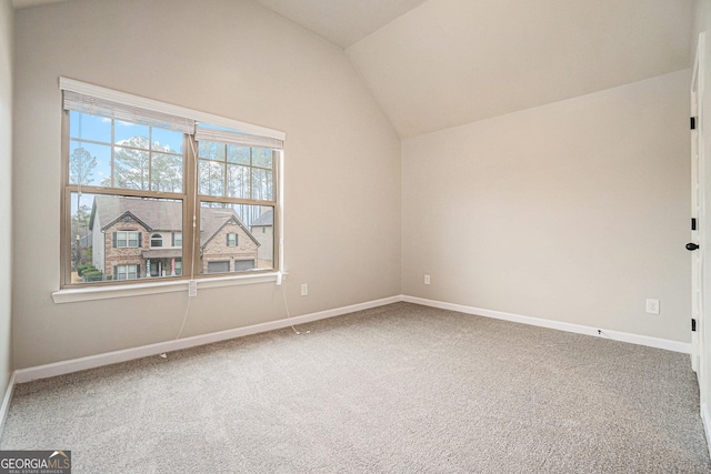 carpeted empty room with vaulted ceiling