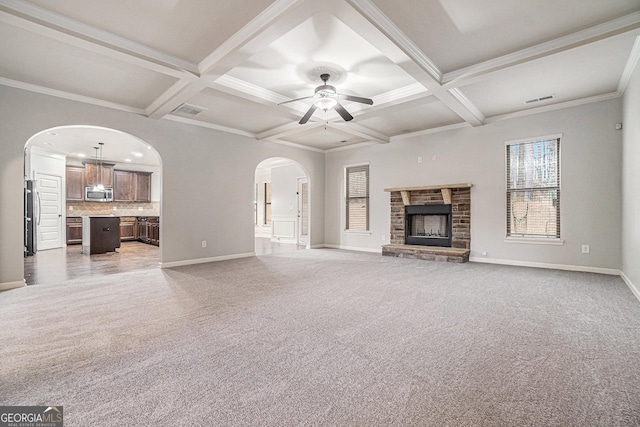 unfurnished living room with light carpet, a stone fireplace, and coffered ceiling