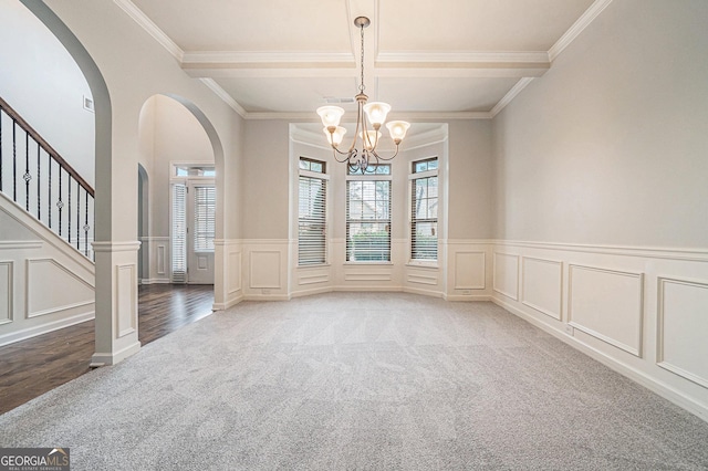 carpeted empty room featuring a notable chandelier, beam ceiling, and ornamental molding