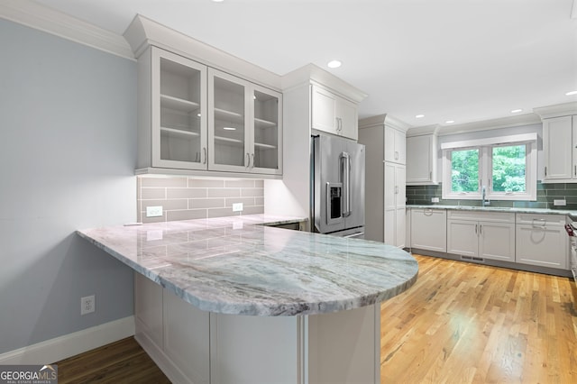 kitchen featuring kitchen peninsula, high end fridge, and light wood-type flooring