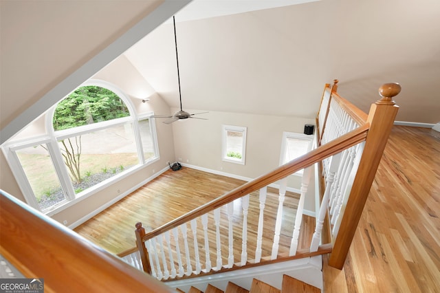 staircase with high vaulted ceiling, ceiling fan, and light wood-type flooring