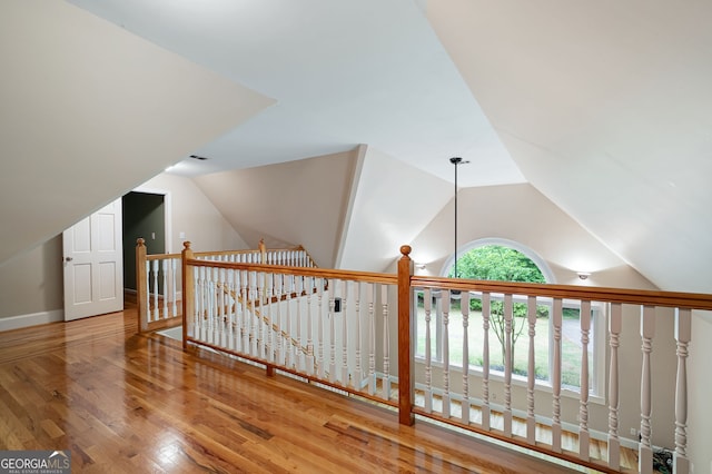 corridor with lofted ceiling and hardwood / wood-style flooring