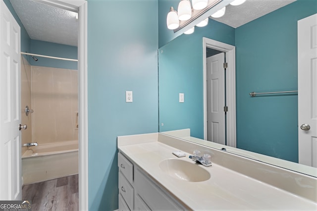 bathroom featuring wood-type flooring, a textured ceiling, vanity with extensive cabinet space, and shower / washtub combination