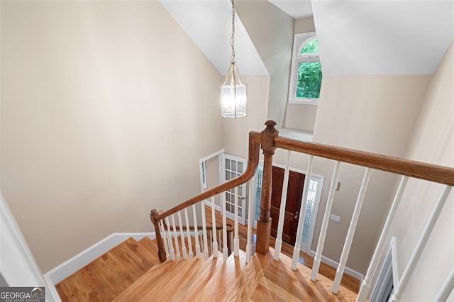 stairs with hardwood / wood-style floors and lofted ceiling