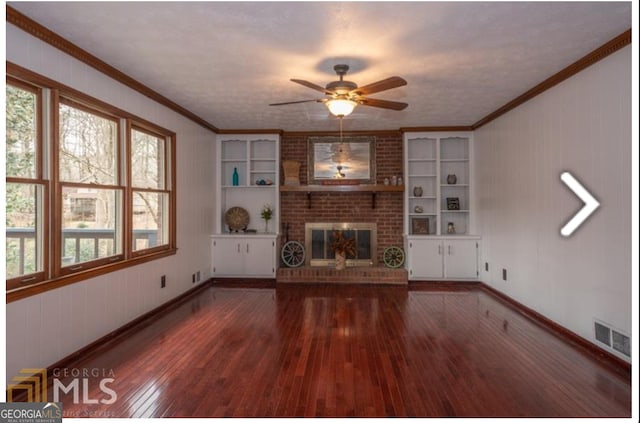 unfurnished living room with ceiling fan, brick wall, dark hardwood / wood-style floors, a fireplace, and ornamental molding