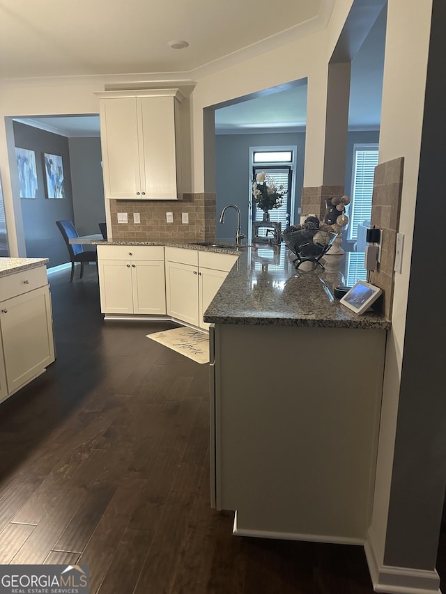 kitchen featuring dark stone counters, white cabinets, sink, dark hardwood / wood-style floors, and kitchen peninsula