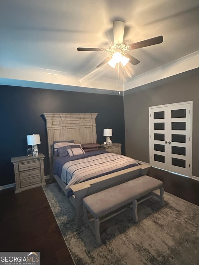 bedroom featuring dark hardwood / wood-style flooring, a tray ceiling, and ceiling fan