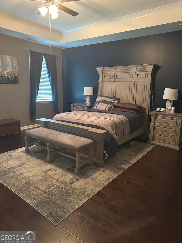 bedroom featuring a tray ceiling, ceiling fan, crown molding, and dark hardwood / wood-style floors