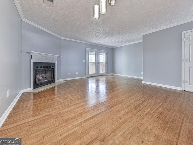 unfurnished living room with a textured ceiling, french doors, light hardwood / wood-style floors, and crown molding