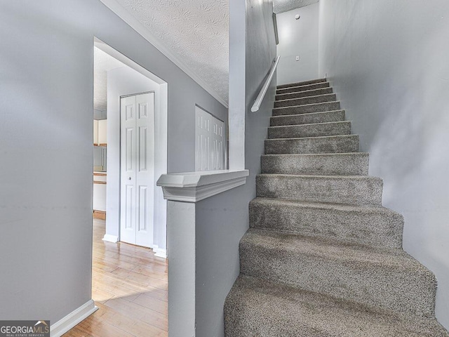 staircase with wood-type flooring and a textured ceiling