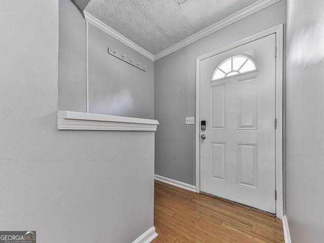 entryway with a textured ceiling, crown molding, and light wood-type flooring