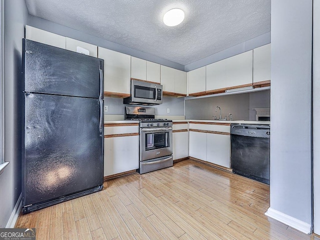 kitchen with white cabinetry, light hardwood / wood-style flooring, black appliances, and a textured ceiling