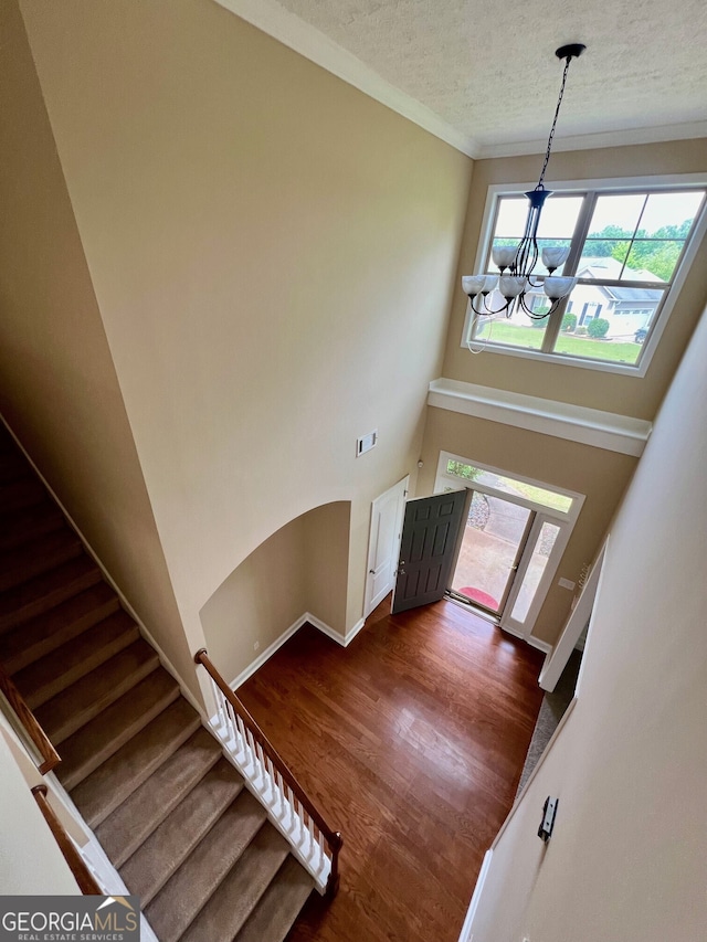 entryway with an inviting chandelier, dark wood-type flooring, a high ceiling, and a textured ceiling