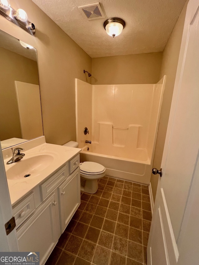 full bathroom featuring vanity, tile flooring, toilet, washtub / shower combination, and a textured ceiling