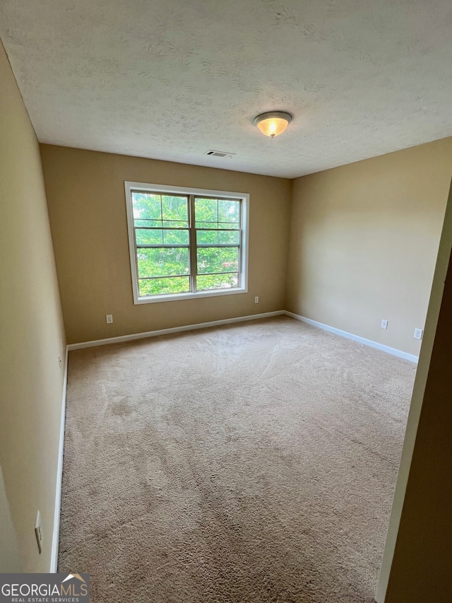 carpeted empty room featuring a textured ceiling