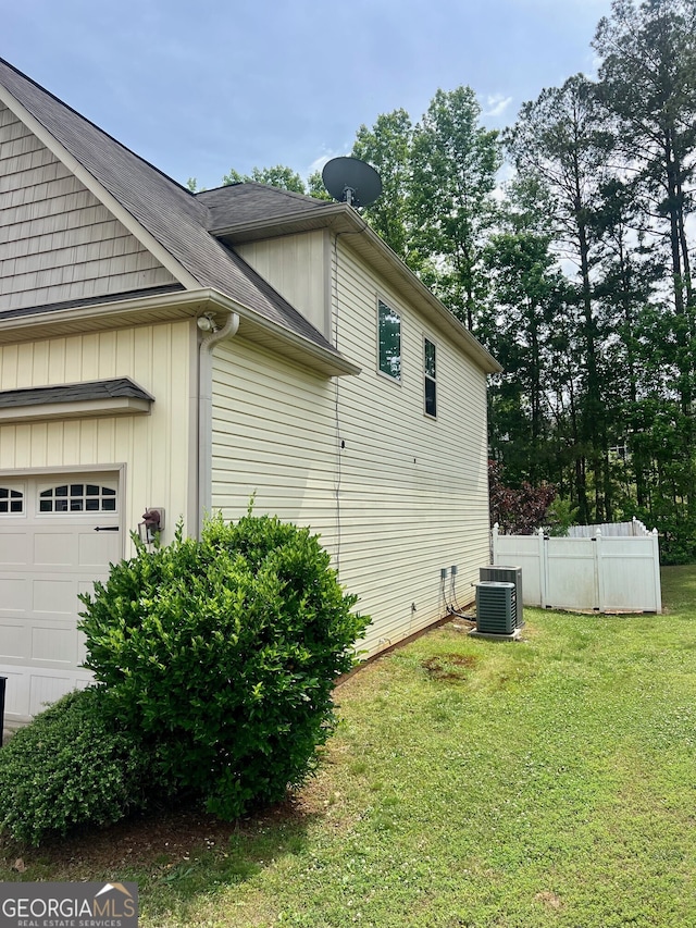 view of property exterior with a lawn, a garage, and central AC unit