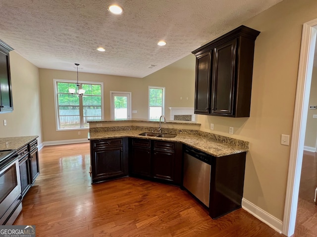 kitchen with appliances with stainless steel finishes, a textured ceiling, sink, light hardwood / wood-style floors, and kitchen peninsula