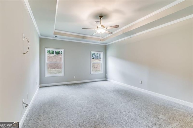 carpeted empty room featuring crown molding, ceiling fan, and a raised ceiling